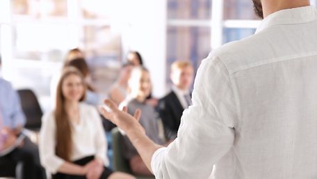 Business-Trainer steht vor einer Gruppe von Menschen